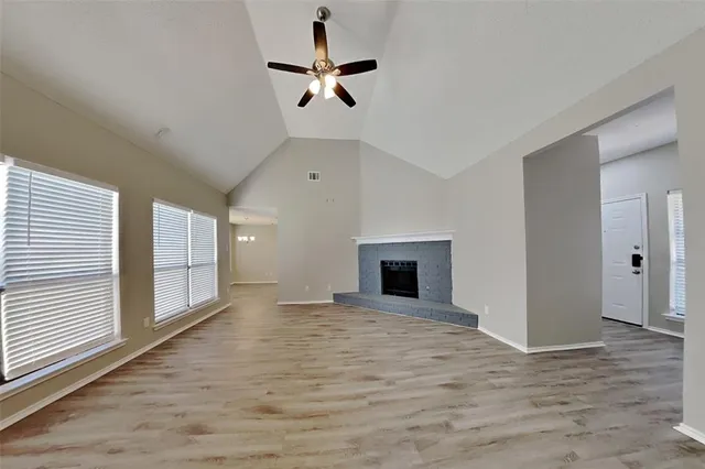 an empty room with windows and fireplace