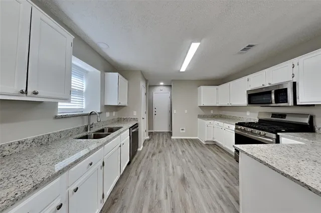 a kitchen with stainless steel appliances granite countertop a stove a sink and a microwave