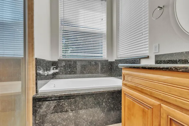 a bathroom with a granite countertop sink and a bathtub