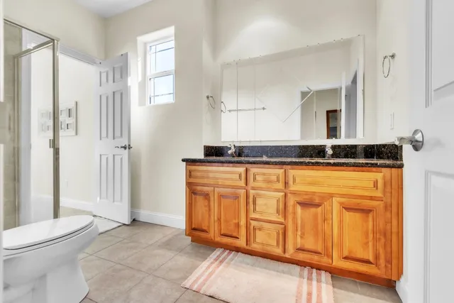 a bathroom with a granite countertop sink a toilet a mirror and shower