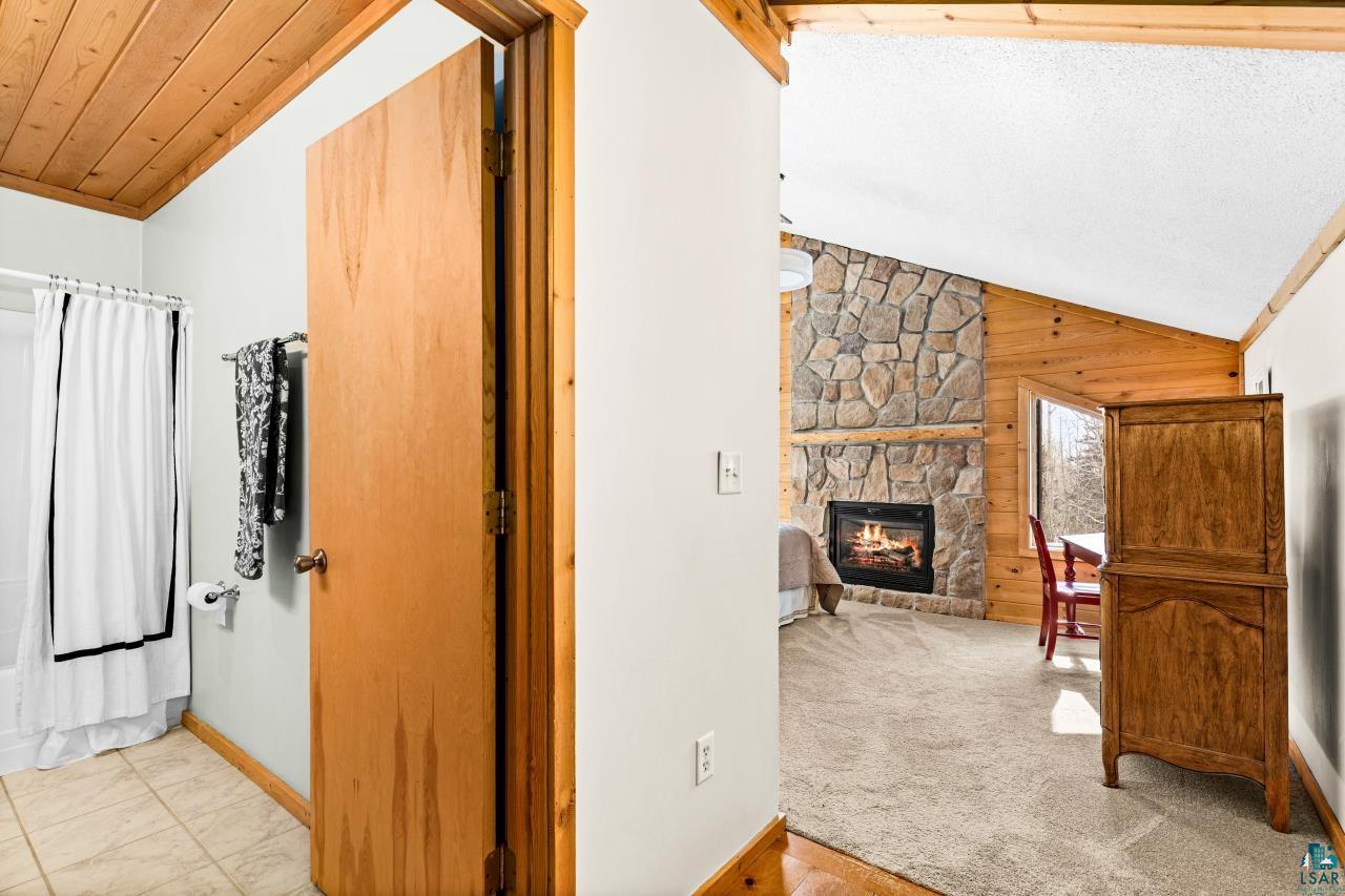 67 Snowshoe Trail Tofte, MN 55615 - Photo 31 of 42 Corridor with lofted ceiling, wood walls, and light carpet