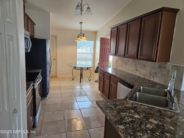 a kitchen with granite countertop a stove a sink and a refrigerator