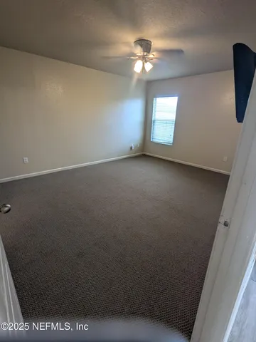 an empty room with windows and fan