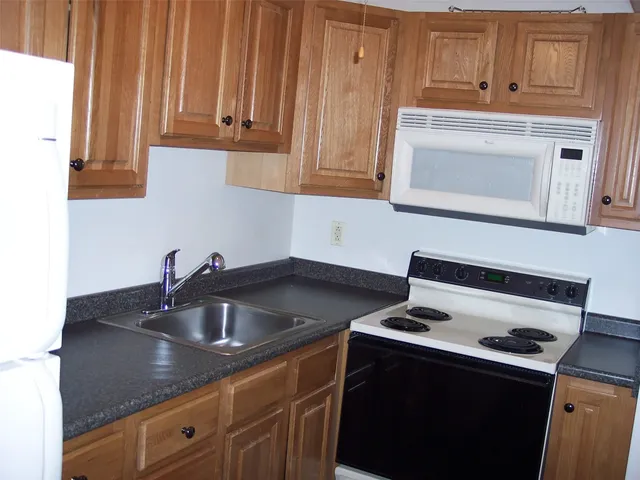 a kitchen with granite countertop a sink stove and cabinets