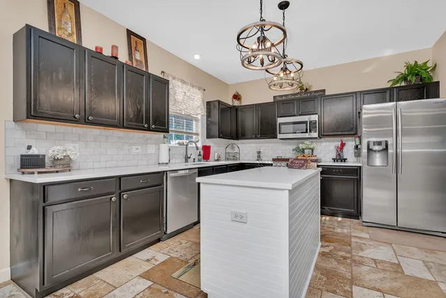 a kitchen with kitchen island granite countertop stainless steel appliances cabinets a sink and a counter space