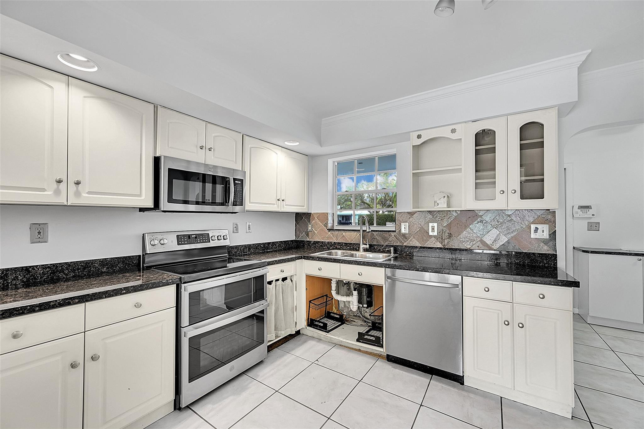 220 Southeast 10th Street Pompano Beach, FL 33060 - Photo 12 of 42 a kitchen with stainless steel appliances granite countertop a sink and cabinets