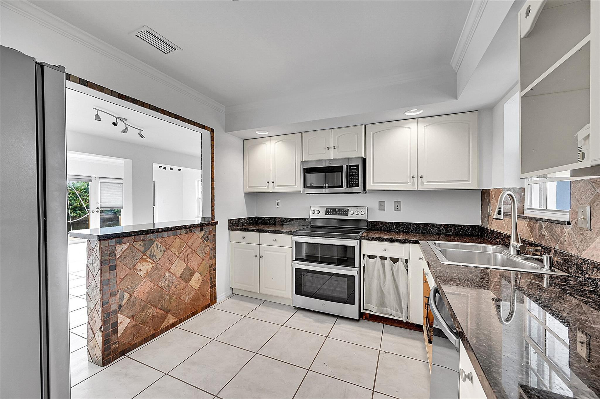 220 Southeast 10th Street Pompano Beach, FL 33060 - Photo 15 of 42 a kitchen with stainless steel appliances granite countertop a stove a sink and a microwave