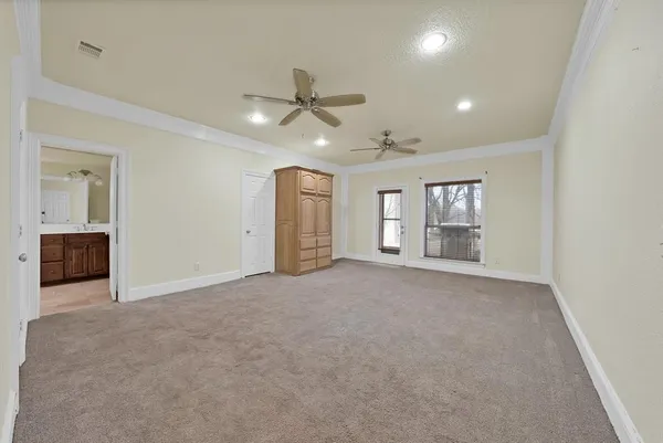 an empty room with chandelier fan and windows