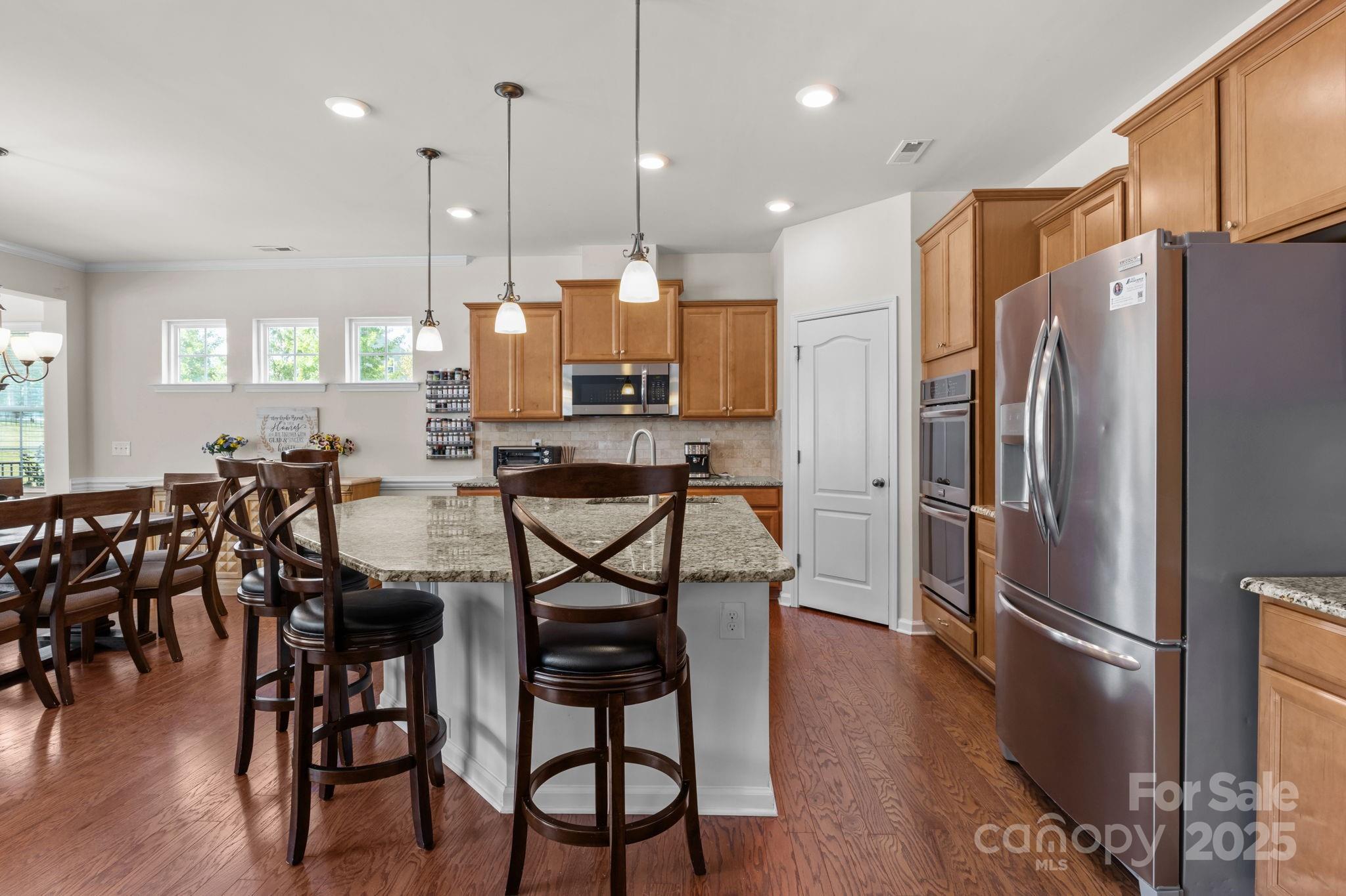 15925 Foreleigh Road Huntersville, NC 28078 - Photo 11 of 48 a kitchen with stainless steel appliances a refrigerator a stove a kitchen island with chairs and wooden floor