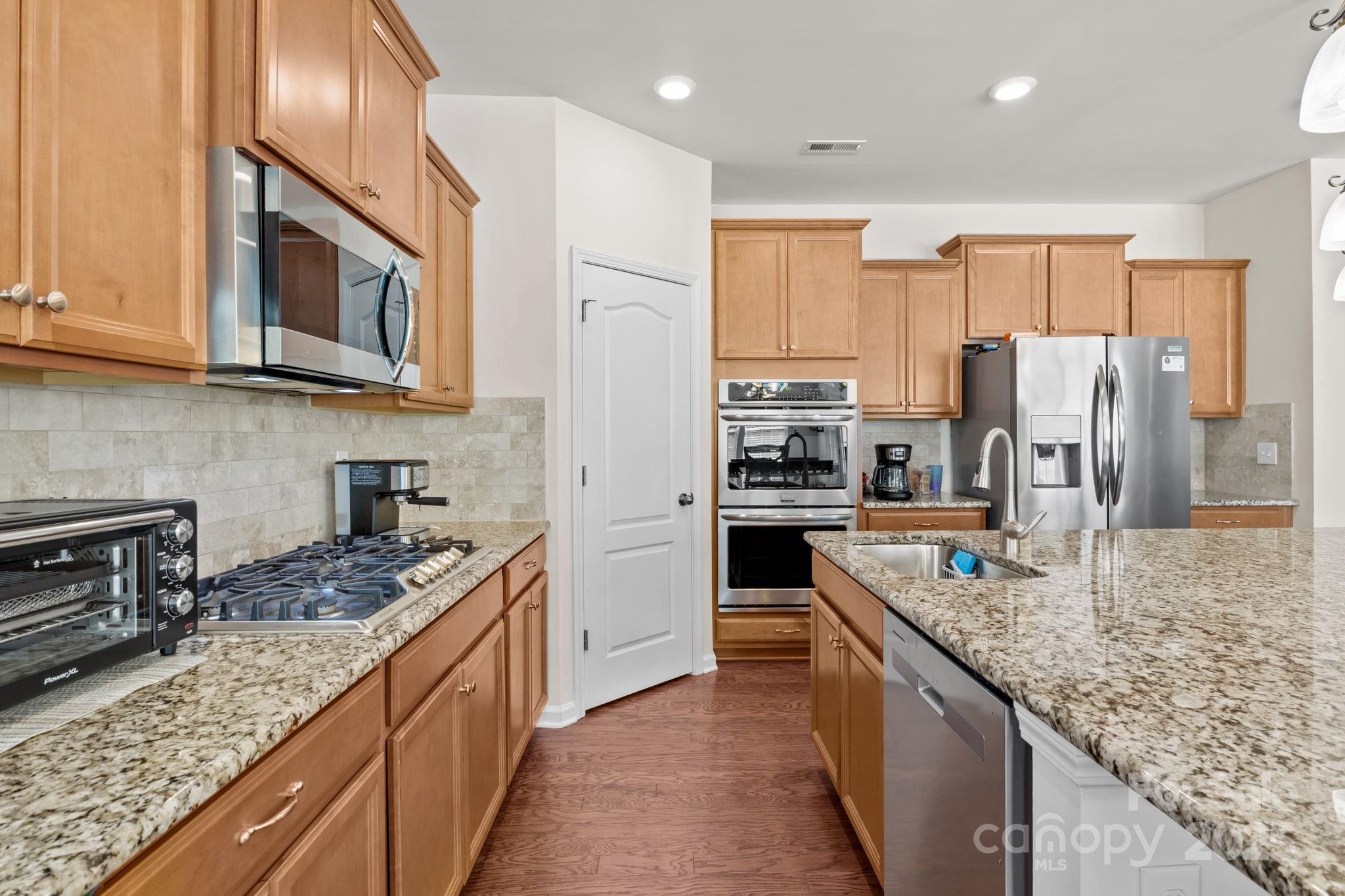 15925 Foreleigh Road Huntersville, NC 28078 - Photo 12 of 48 a kitchen with stainless steel appliances granite countertop a refrigerator a stove top oven a sink and dishwasher