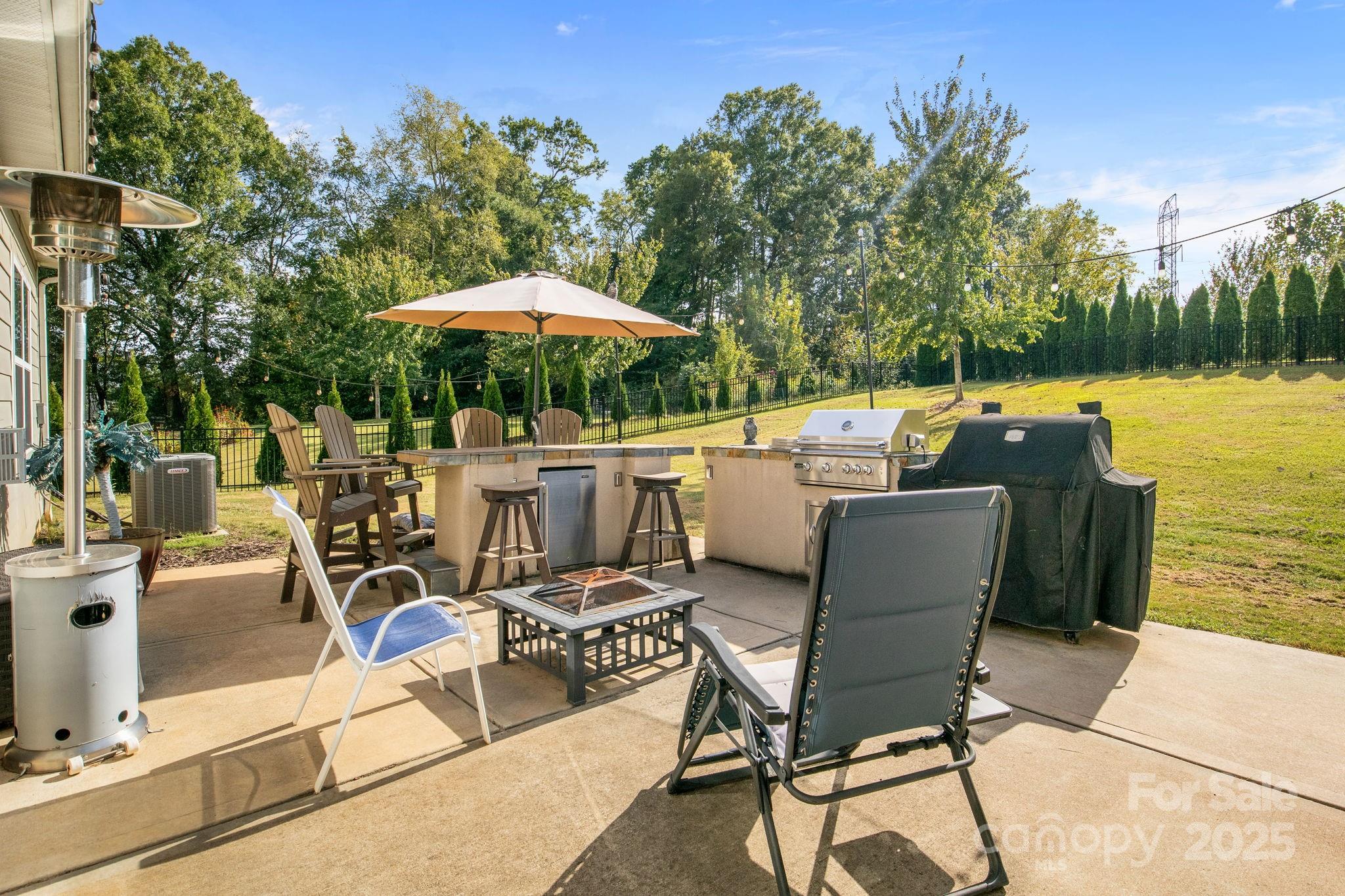 15925 Foreleigh Road Huntersville, NC 28078 - Photo 39 of 48 a view of a patio with table and chairs under an umbrella with large trees