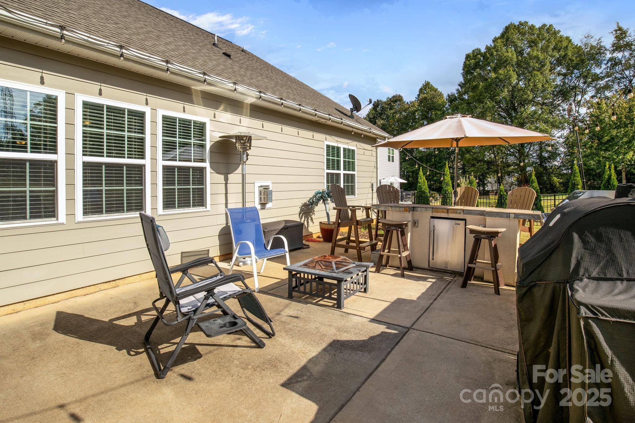15925 Foreleigh Road Huntersville, NC 28078 - Photo 40 of 48 a view of a patio with table and chairs under an umbrella with a barbeque