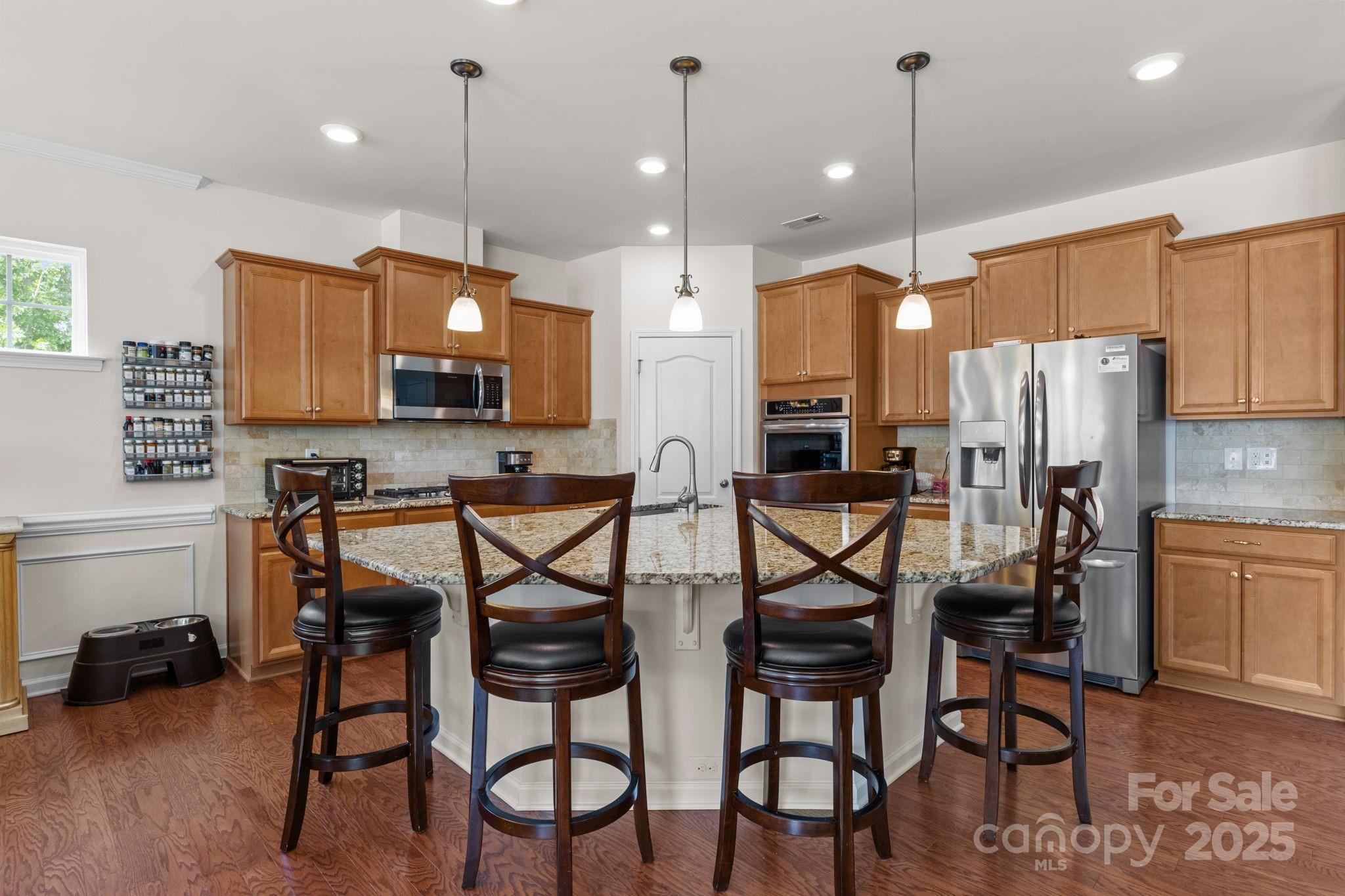 15925 Foreleigh Road Huntersville, NC 28078 - Photo 10 of 48 a kitchen with stainless steel appliances kitchen island granite countertop a table chairs and a refrigerator