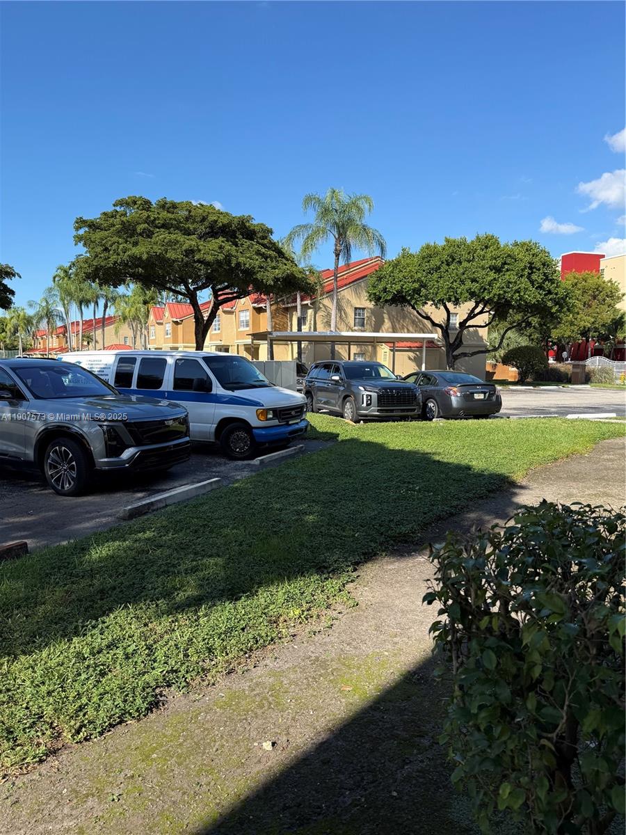 18308 Northwest 68th Avenue, Unit F Hialeah, FL 33015 - Photo 14 of 17 a view of a house with garden and car parked
