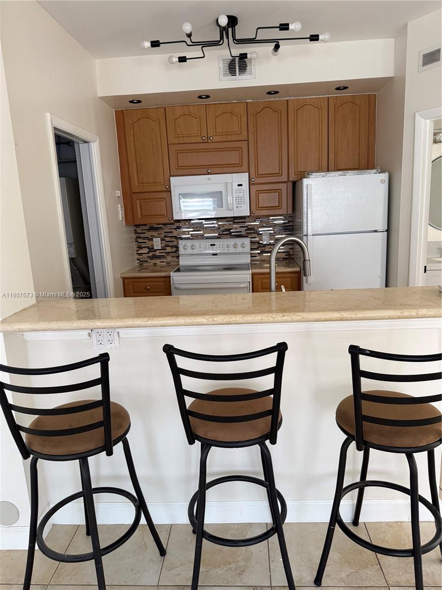 18308 Northwest 68th Avenue, Unit F Hialeah, FL 33015 - Photo 7 of 17 a kitchen with a table chairs and a refrigerator