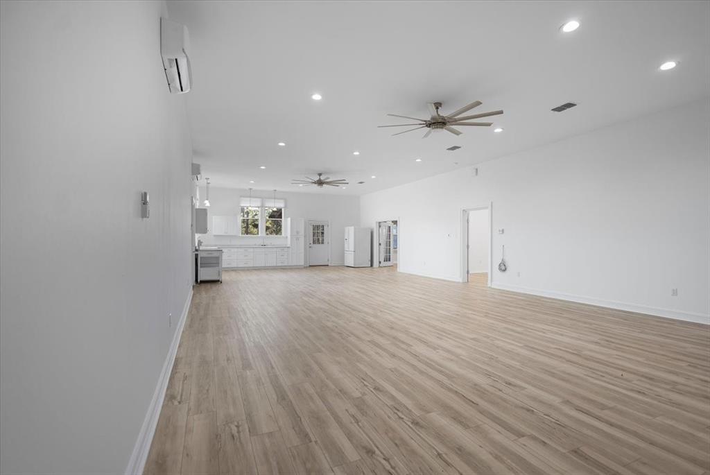 6990 Pin Oak Road Big Sandy, TX 75755 - Photo 10 of 40 an empty room with wooden floor a ceiling fan and kitchen view