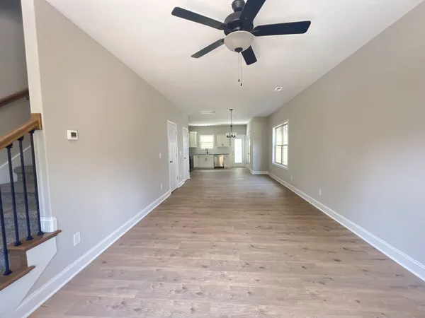 an empty room with ceiling fan and windows