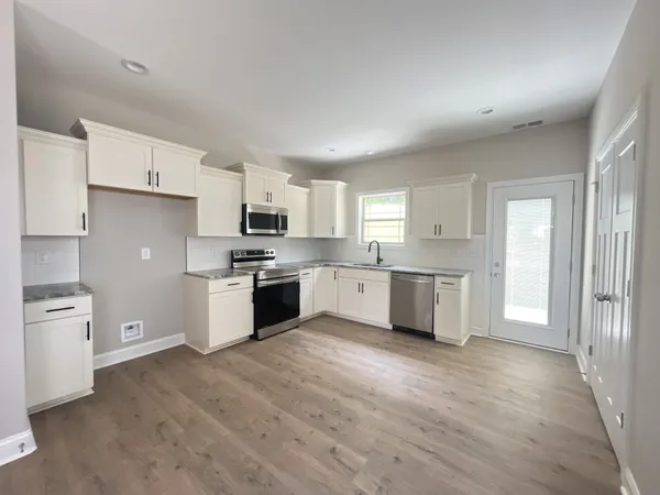 a large kitchen with cabinets wooden floor and stainless steel appliances