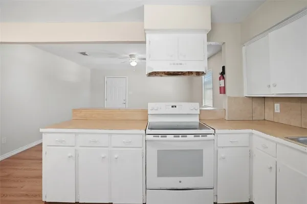 a kitchen with cabinets appliances and wooden floor