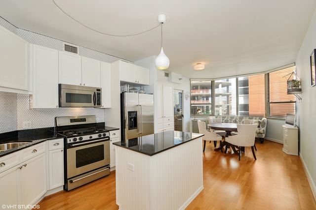 720 West Randolph Street, Unit 808 Chicago, IL 60661 - Photo 2 of 15 a kitchen with a table chairs refrigerator and cabinets