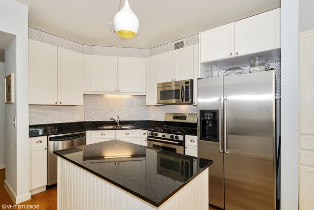 720 West Randolph Street, Unit 808 Chicago, IL 60661 - Photo 5 of 15 a kitchen with a sink a counter top space cabinets and stainless steel appliances