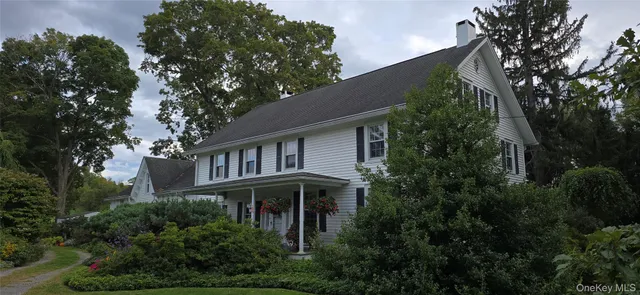 a front view of a house with plants and trees