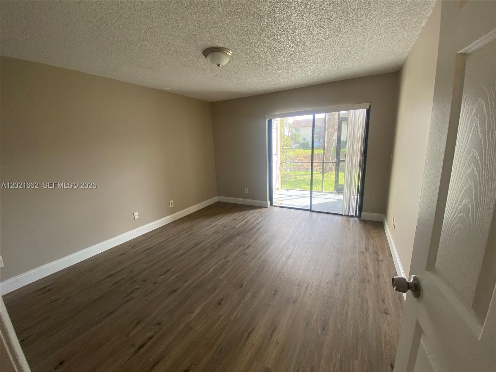 3263 Kirk Road, Unit 2 Lake Worth, FL 33461 - Photo 9 of 14 an empty room with wooden floor and windows