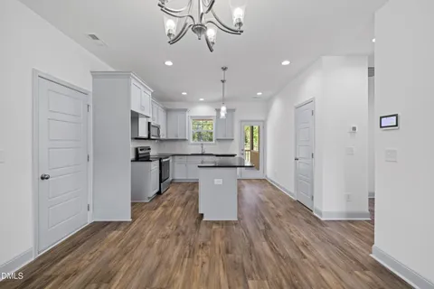 a kitchen with kitchen island wooden floors appliances and cabinets