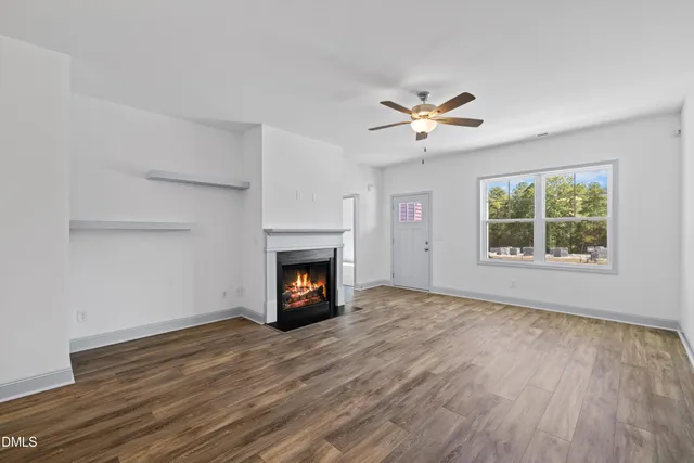 an empty room with windows fireplace and a kitchen view