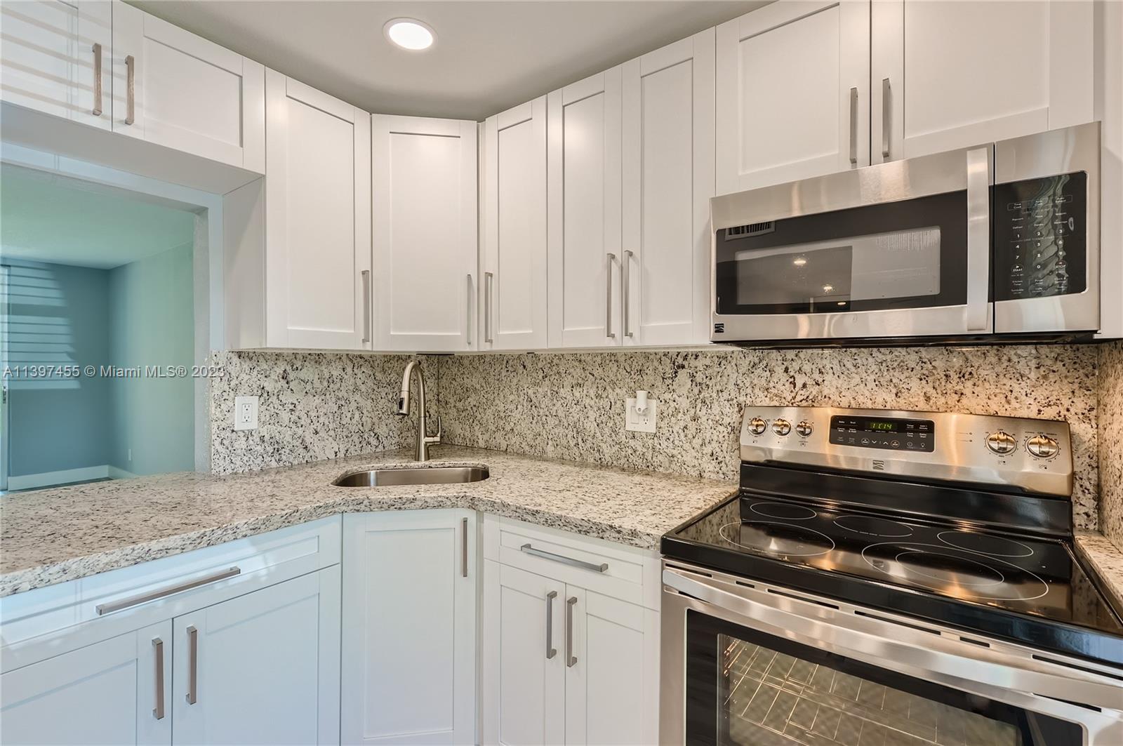 a kitchen with granite countertop white cabinets and a stove top oven