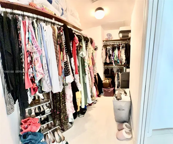 a view of walk in closet with clothes and shoes