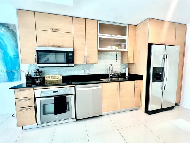 a kitchen with stainless steel appliances granite countertop a stove a sink and a refrigerator