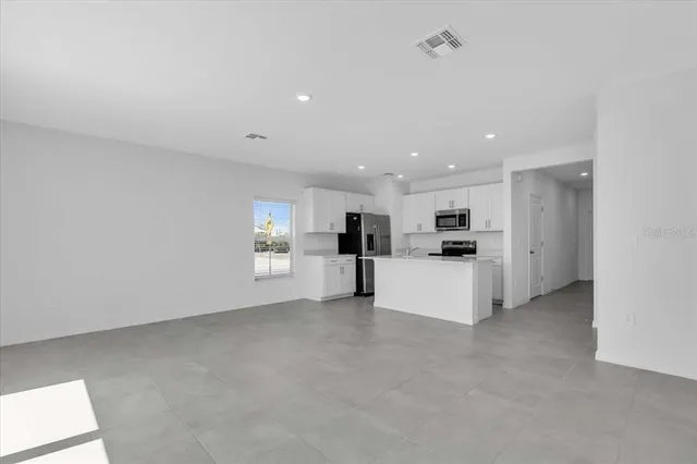 a view of kitchen with kitchen island white cabinets and refrigerator