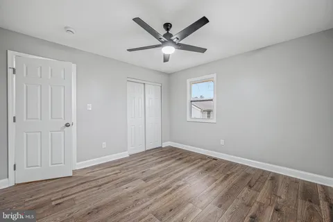 an empty room with wooden floor and ceiling fan