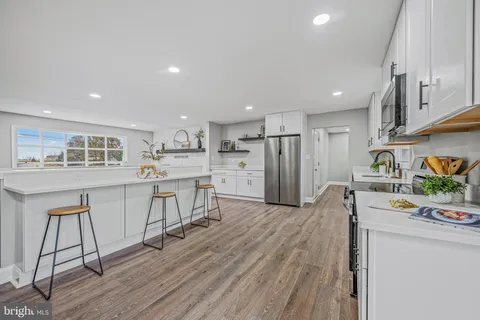 a kitchen with kitchen island wooden floors appliances and cabinets