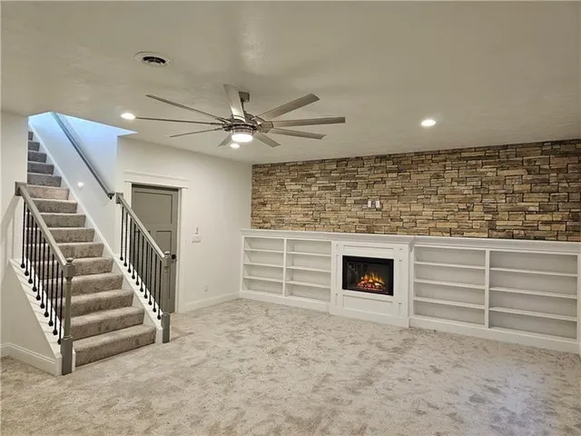 a view of an empty room with stairs and a ceiling fan