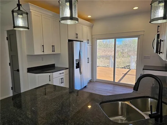 a kitchen with stainless steel appliances granite countertop a refrigerator a stove and a sink with wooden floor