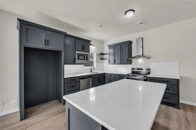 a large white kitchen with stainless steel appliances a sink dishwasher stove and refrigerator