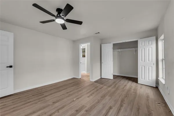 an empty room with wooden floor and a ceiling fan