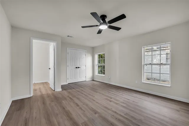 a view of an empty room with wooden floor and a window