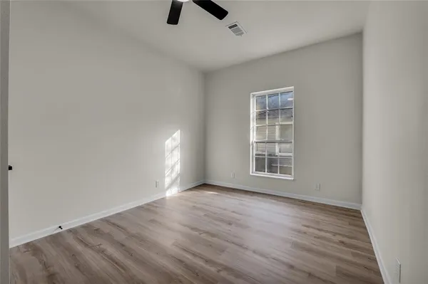 an empty room with ceiling fan and windows