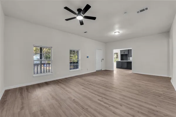 a view of an empty room with a window and wooden floor