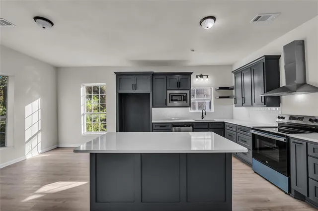 a large kitchen with stainless steel appliances a large counter top stove and refrigerator