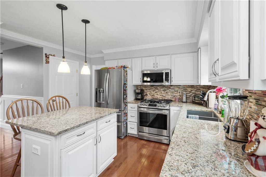 104 Camelot Circle Coraopolis, PA 15108 - Photo 10 of 33 a kitchen with stainless steel appliances kitchen island granite countertop a stove a sink dishwasher a refrigerator and a fireplace with wooden floor