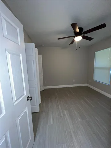 an empty room with ceiling fan and window