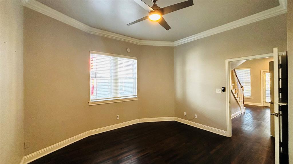 4511 Junius Street Dallas, TX 75246 - Photo 3 of 16 Spacious room featuring dark wood-finish flooring, light-toned walls, and white crown molding. Could be a 4th bedroom.