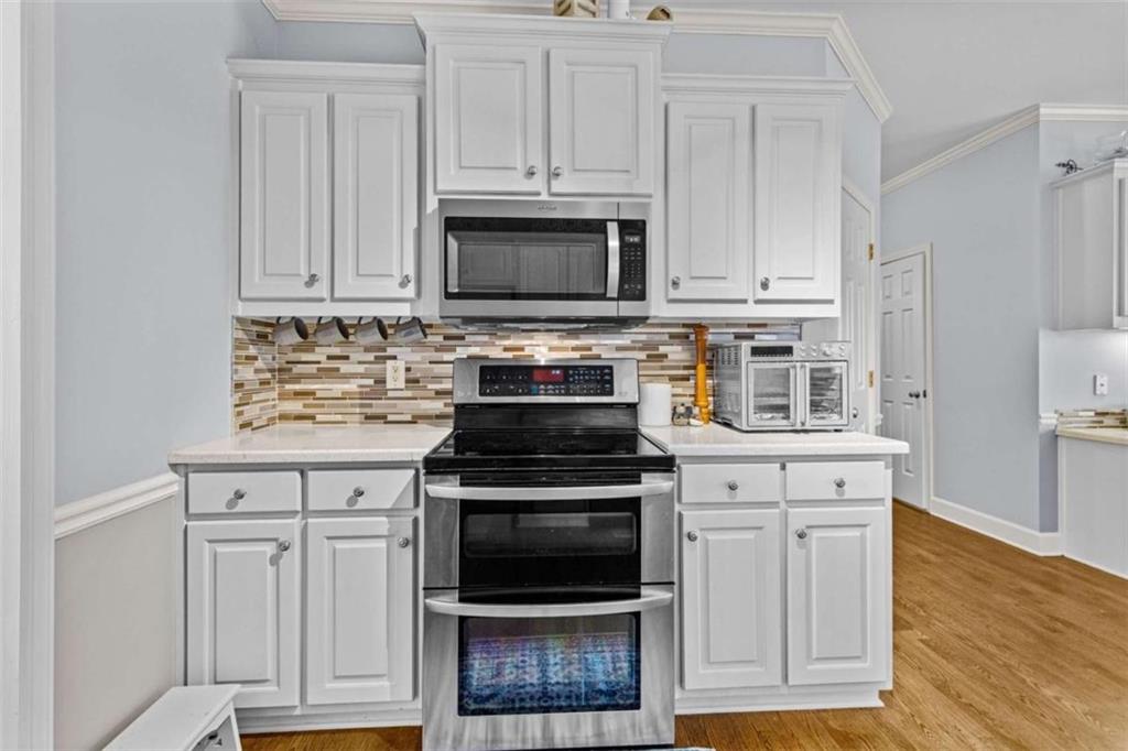 1148 Maple Creek Ridge Loganville, GA 30052 - Photo 17 of 46 a kitchen with white cabinets and black appliances