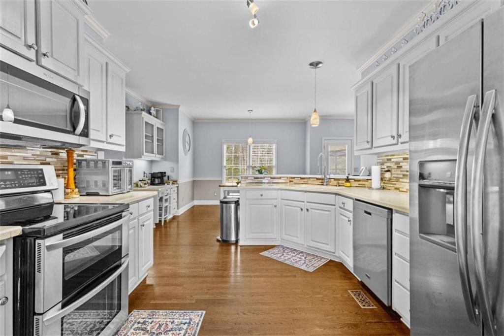 1148 Maple Creek Ridge Loganville, GA 30052 - Photo 18 of 46 a kitchen with stainless steel appliances granite countertop a stove top oven a sink dishwasher a refrigerator and cabinets with wooden floor