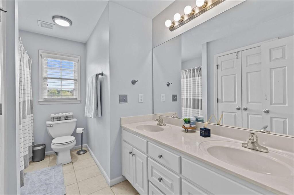 1148 Maple Creek Ridge Loganville, GA 30052 - Photo 24 of 46 a bathroom with a double vanity sink a mirror and a toilet