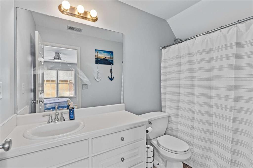 1148 Maple Creek Ridge Loganville, GA 30052 - Photo 37 of 46 a bathroom with a sink a toilet a mirror and shower curtain